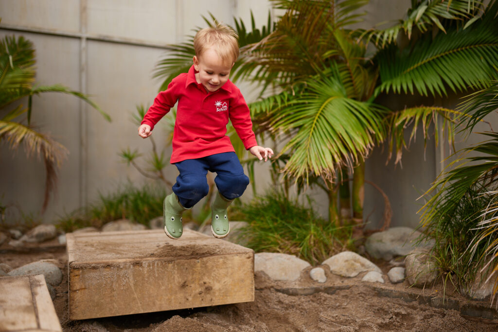 A boy jumping on a platform happily.